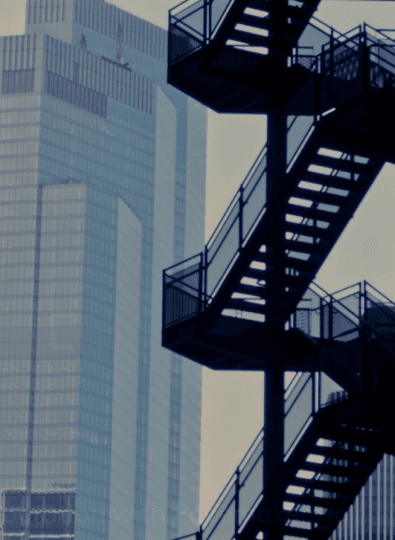 Skyscrapers in a blue haze behind a black metal external staircase