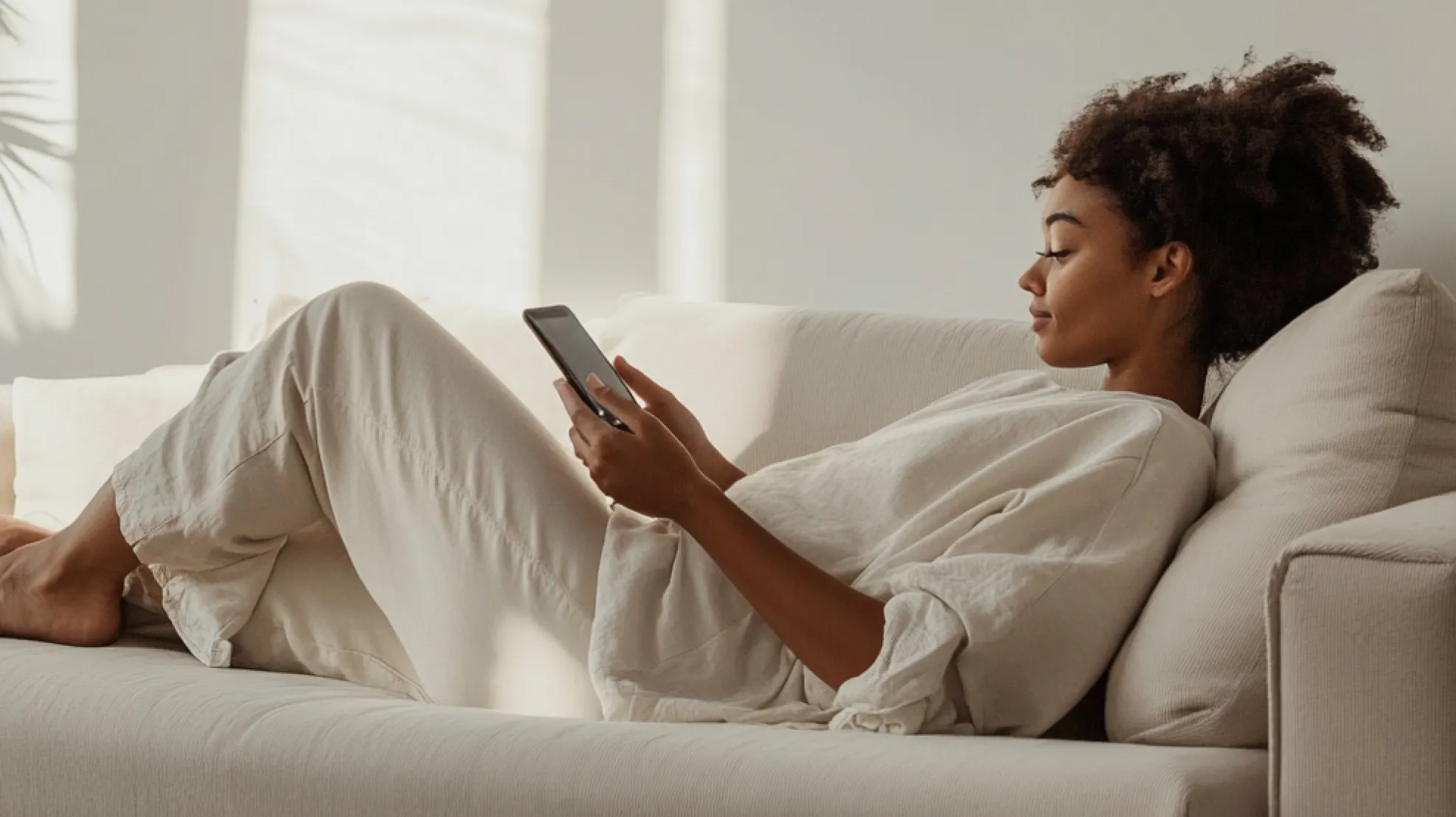 Person scrolling on their mobile phone on the sofa